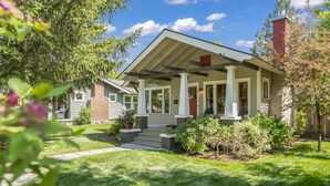 A single-story house with a front porch, a brick chimney, and a well-maintained lawn. - Historic Craftsman Bungalow, Just Steps to Downtown ~HOT TUB!~ (Bend)