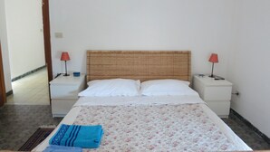 A bedroom with a bed, two nightstands, two lamps, a blue towel, and a patterned bedspread. - Pompei, Vesuvio and Naples bay view (Trecase)