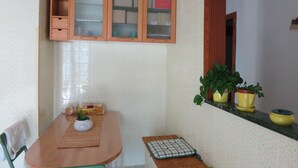 A small kitchen with a wooden table, a cabinet with glass doors, and a window with a view. - Pompei, Vesuvio and Naples bay view (Trecase)