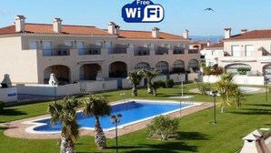 Un hôtel doté d’une piscine, de palmiers et surplombant un ciel bleu azur.