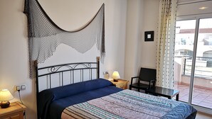 Une chambre à coucher avec un lit, une chaise, une table de chevet avec une lampe et un balcon avec vue.