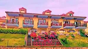 A multi-story building with balconies and a staircase leading to the entrance. - Casa de Las Flores Apartment with private garden in front of the beach of Comillas (Comillas)