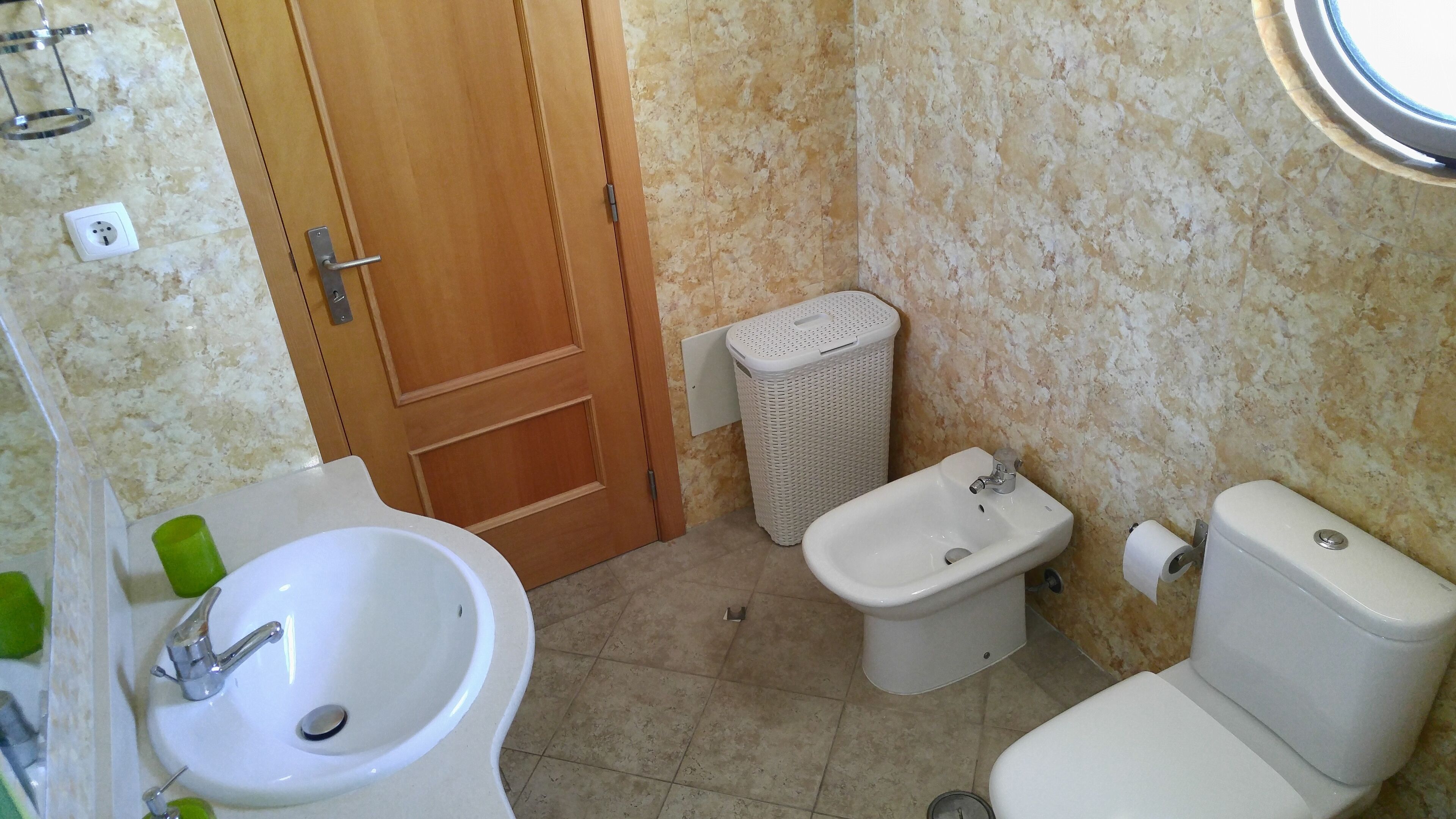 Une salle de bain équipée d’un lavabo, d’un bidet, de toilettes et d’une porte en bois.