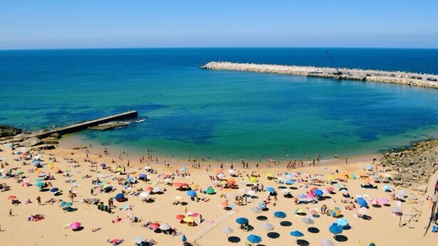 A beach with numerous colorful umbrellas and people enjoying the sunny weather. - I L❤️VE U! Villa. Sea view! SPA! Heated Pool! Cinema! Private Chef! (Ericeira)