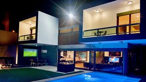 A modern two-story house with a swimming pool, outdoor seating, and a flat-screen TV. - I L❤️VE U! Villa. Sea view! SPA! Heated Pool! Cinema! Private Chef! (Ericeira)