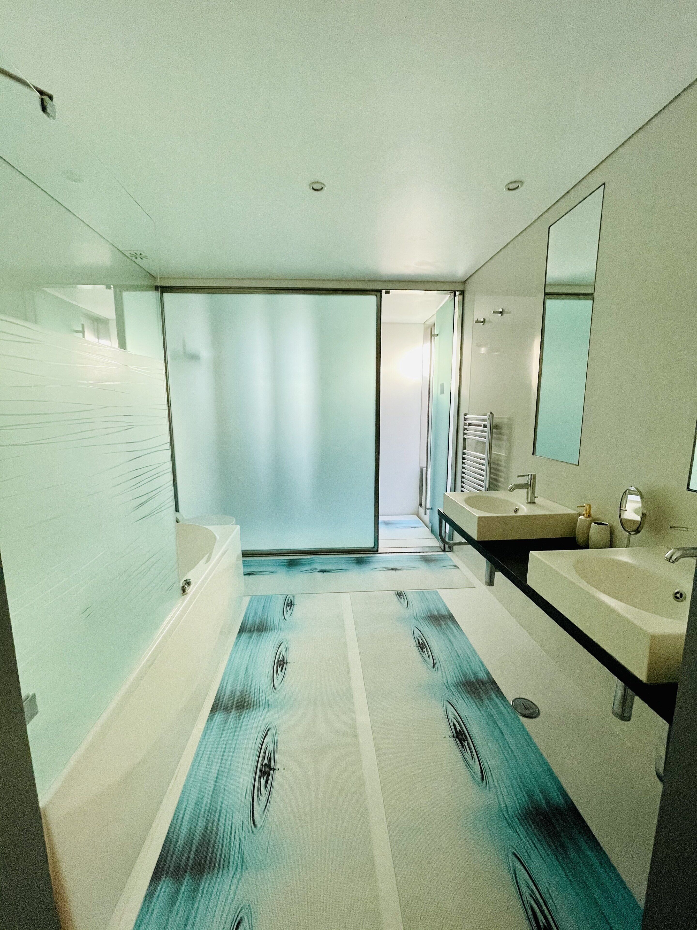 A modern bathroom with a large bathtub, two sinks, and a mirror.