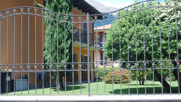 Uma área cercada com um edifício com varandas e um jardim.