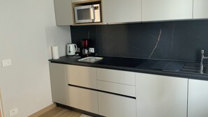 Uma cozinha moderna com bancada preta, eletrodomésticos de aço inoxidável e armários claros.