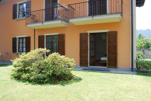 A two-story building with balconies, wooden shutters, and a small garden area. - House with garden a few steps from the beach and the center (Cannobio)