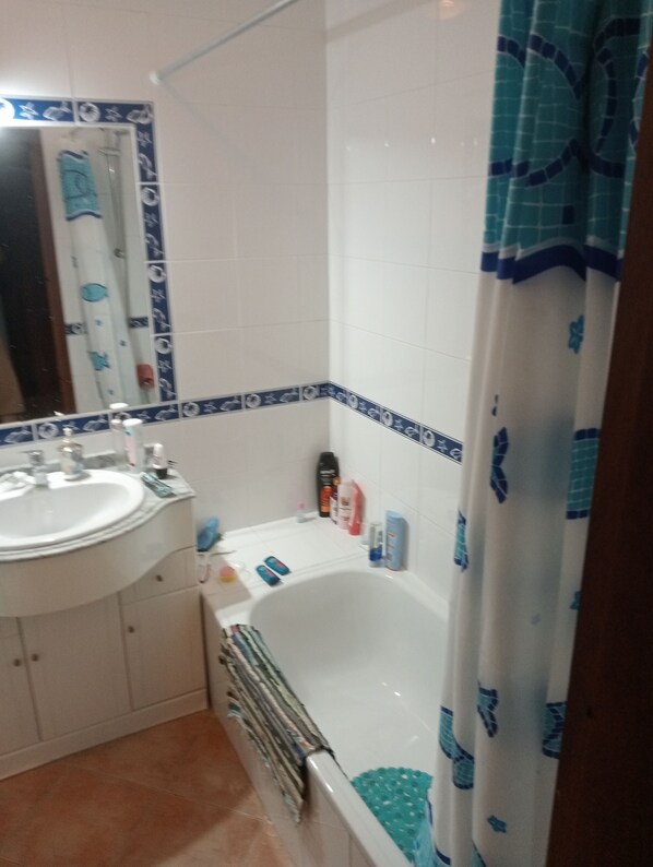 A bathroom with a white sink, mirror, and bathtub. There are toiletries on the sink and the bathtub. - Apartment In A Quiet Location At Castelos Da Rocha (Portimão)