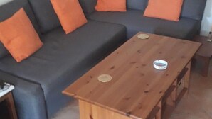 Un salon avec un canapé gris, des coussins orange et une table basse en bois.