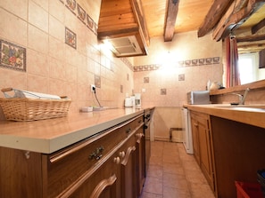 Una cocina compacta con armarios de madera, horno empotrado y salpicadero de azulejos.