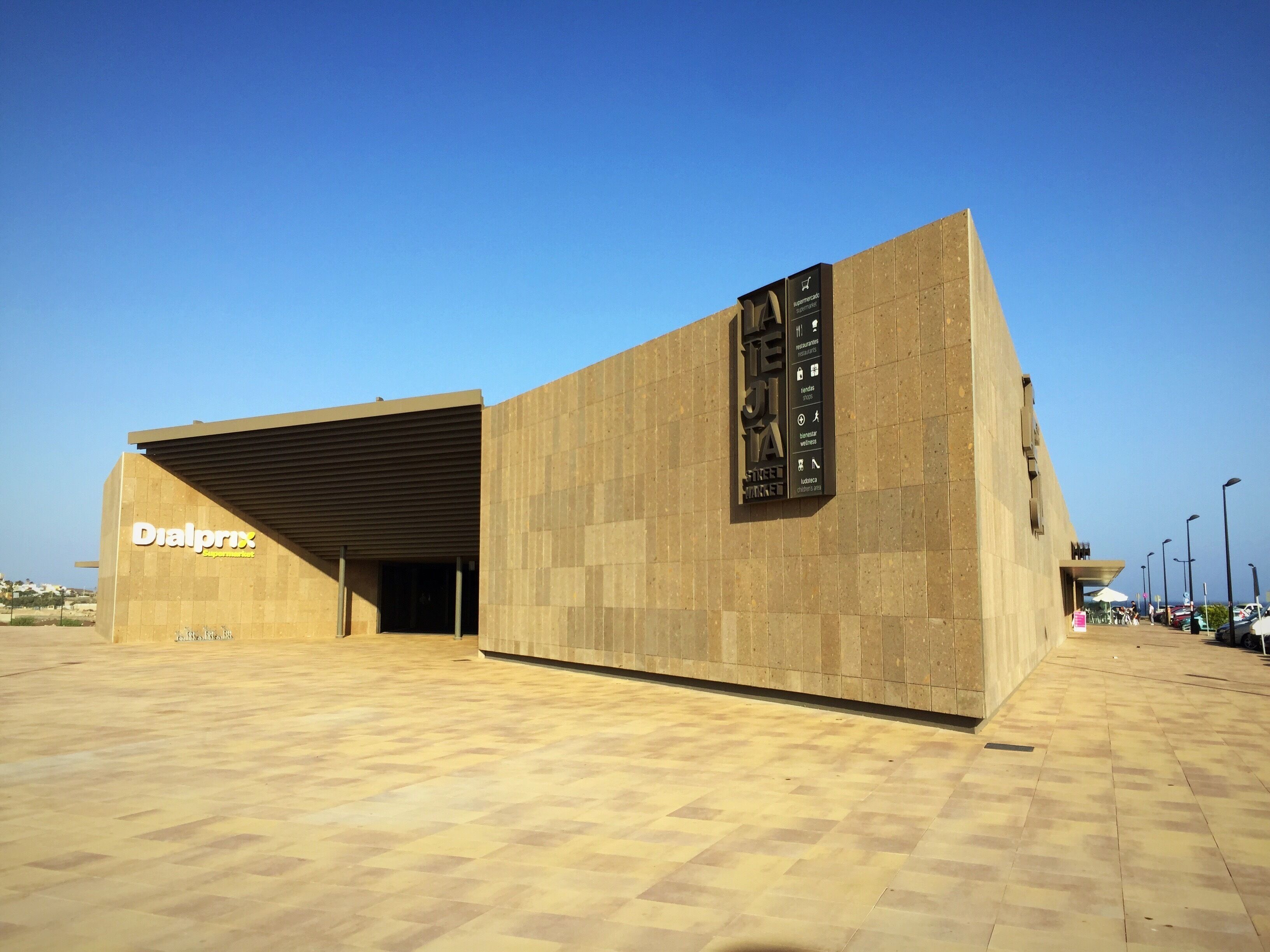 Un edificio moderno con un llamativo letrero de 'Dialprix' a la izquierda.