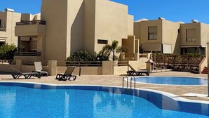 Ein Pool mit Liegestühlen und blauem Himmel.