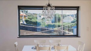 Ein Essbereich mit Tisch und Stühlen, einer Kristallleuchter und einem großen Fenster mit Blick auf Grünflächen und eine Brücke.