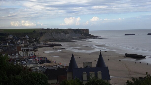 A coastal town with a beach, houses, and cliffs.