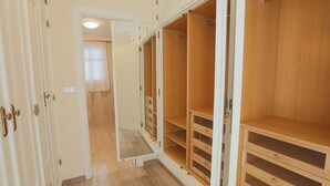 A walk-in closet with open doors, wooden shelves, and drawers.