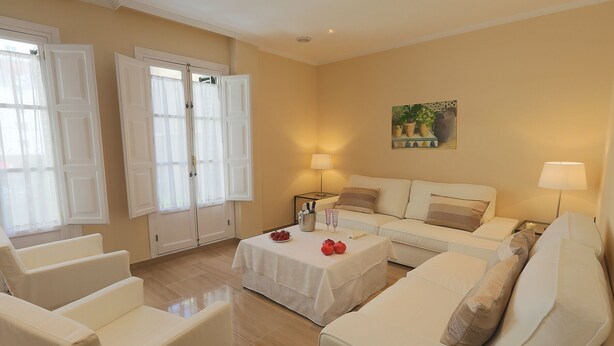 A living room with a white sofa, a coffee table with decorative items, and a painting on the wall.