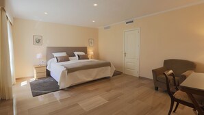 A hotel room with a large bed, bedside tables, a chair, and a door.