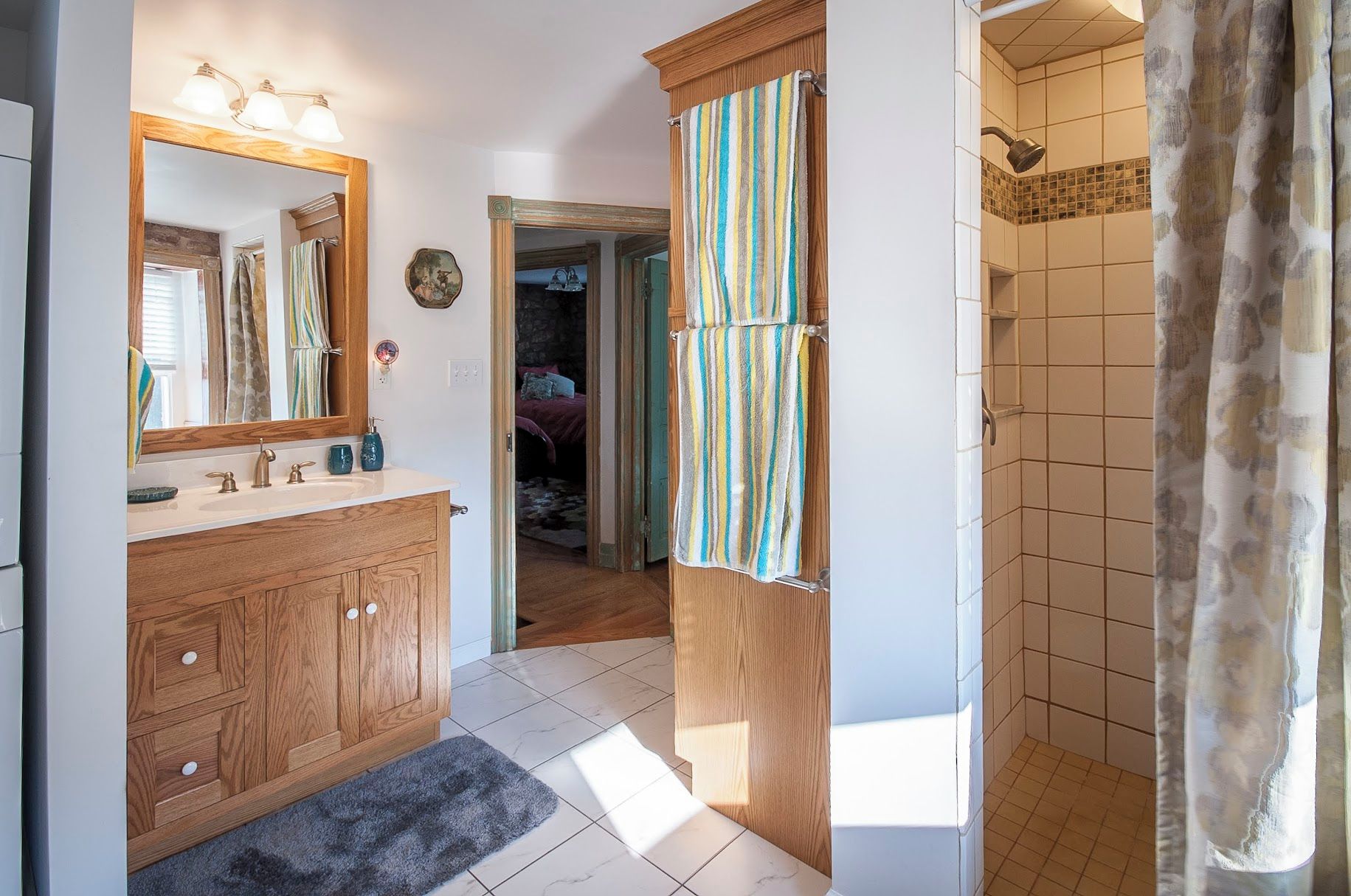 Een badkamer met een houten wastafelmeubel, een spiegel en een douche met gordijn.