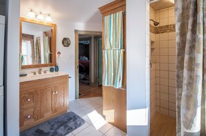 A bathroom with a wooden vanity, a mirror, and a shower with a curtain. - Frush Farm Bed & Breakfast (Reinholds)