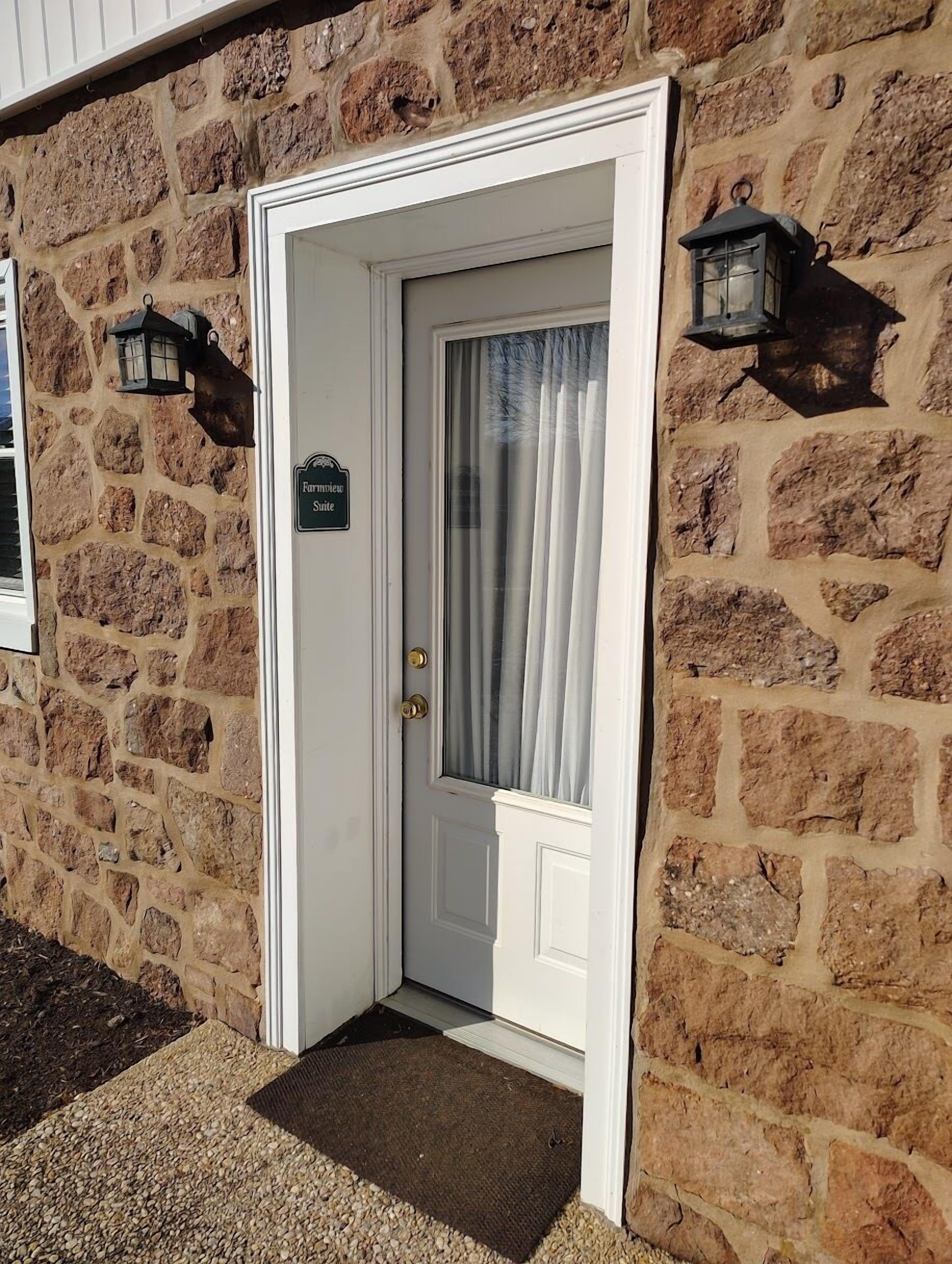 A white door with a sign reading "Farmview Suite" on a stone building.