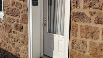 A white door with a sign reading "Farmview Suite" on a stone building.