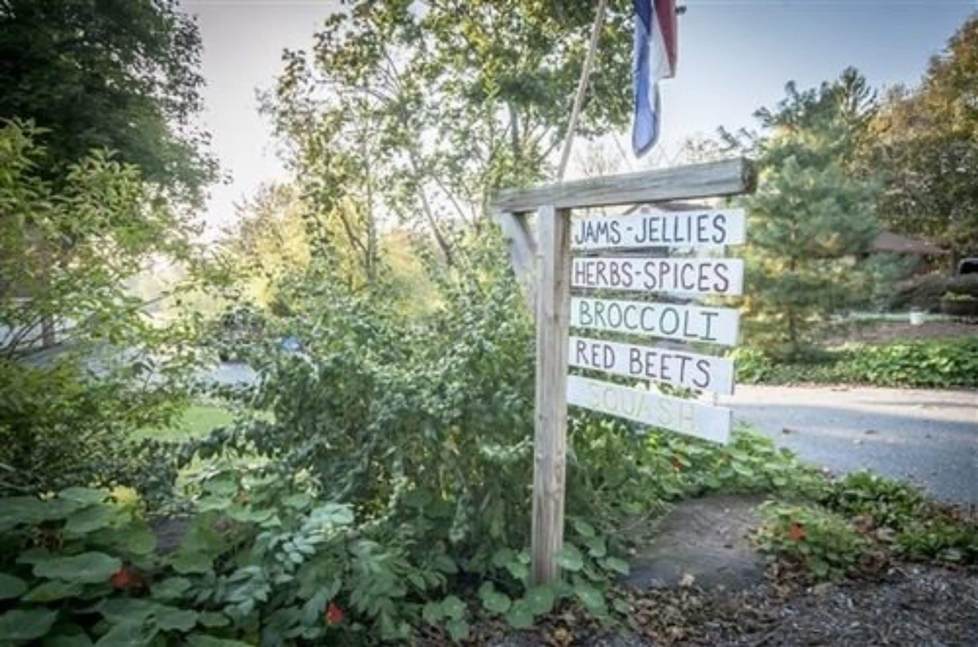 En träskylt med en lista över olika sorters grönsaker, till exempel sylt, gelé, örter, kryddor, broccoli och rödbetor.
