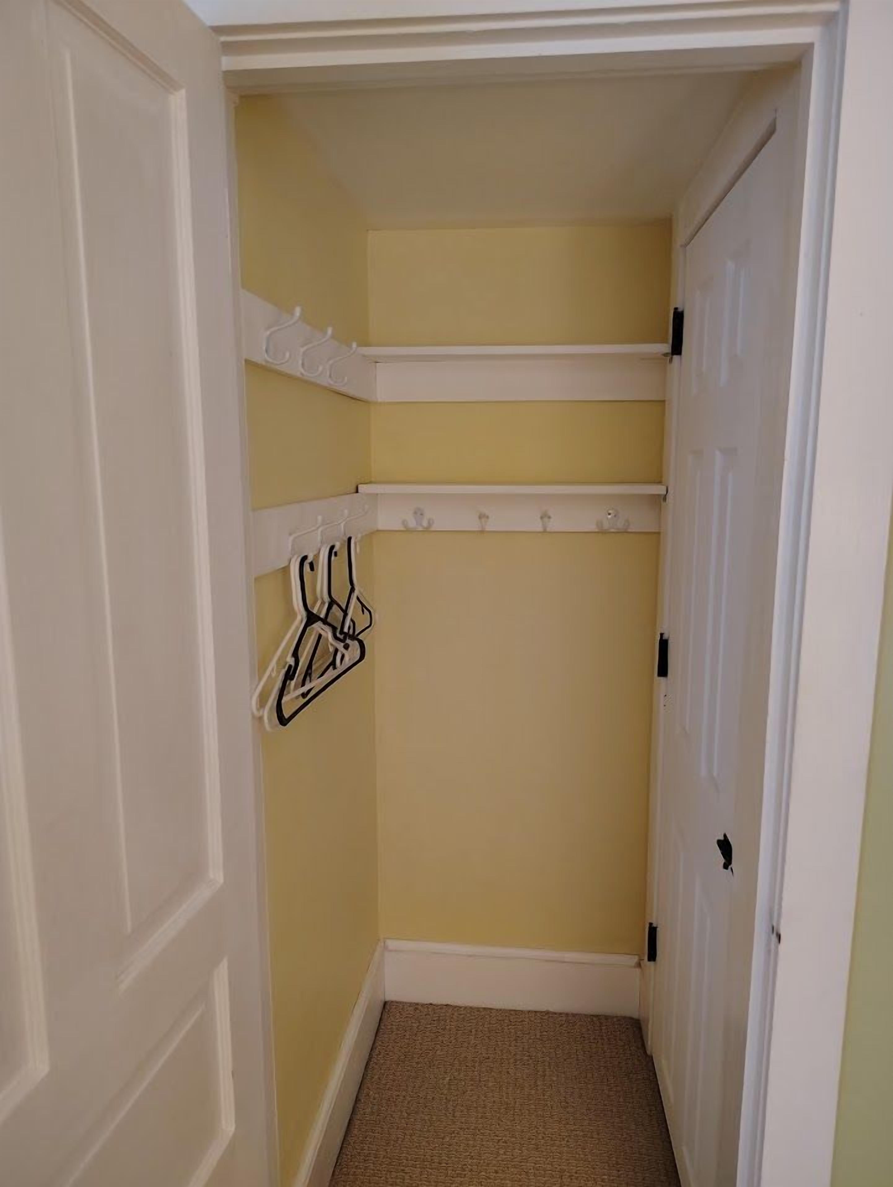 Een smalle gang met een gele muur, een witte deur en een vloerbedekking.