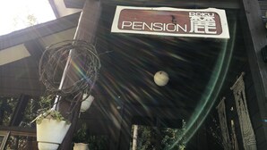 Un edificio de madera con un letrero que dice "PENSION JEE" y un aro de baloncesto.