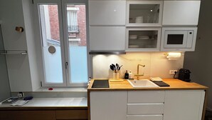 A modern kitchen with white cabinets, a wooden countertop, and a built-in microwave. - Beautiful & quiet flat, ideally located (Paris)