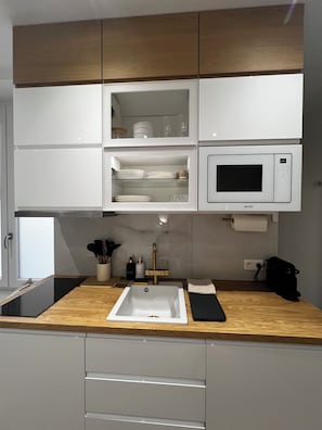 Una cocina con microondas integrado, un fregadero y armarios sobre la encimera.