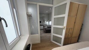 A modern bedroom with a large window, a wardrobe, and a view into the living area. - Beautiful & quiet flat, ideally located (Paris)