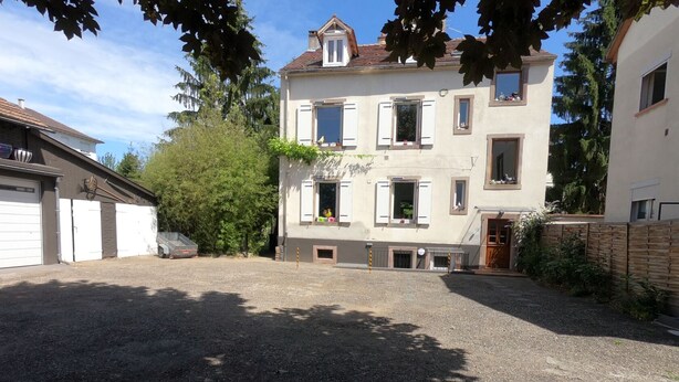 Ein zweistöckiges Gebäude mit einem Schotterweg, einer Garage und einem Holzzaun.