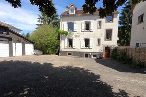 Un bâtiment à deux étages avec une allée gravillonnée, un garage et une clôture en bois.
