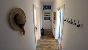 Ein Flur mit Holzboden, einer Tür am Ende und einem Hut an der Wand.