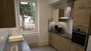 Eine moderne Küche mit Einbauofen, Kaffeemaschine und einem Fenster mit Blick ins Freie.