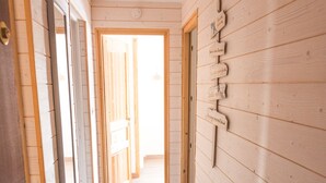 A hallway with wooden walls and a tiled floor, leading to an open area.