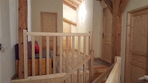 Uma escada de madeira com corrimão leva a um quarto com sofá e porta.