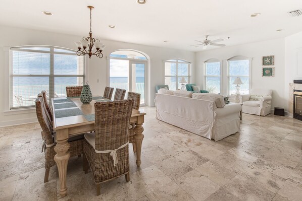 A spacious living area with a dining table, wicker chairs, a sofa, and a fireplace.