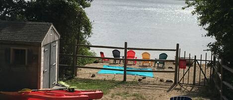 Vista para o lago com um pequeno galpão, caiaques e cadeiras.