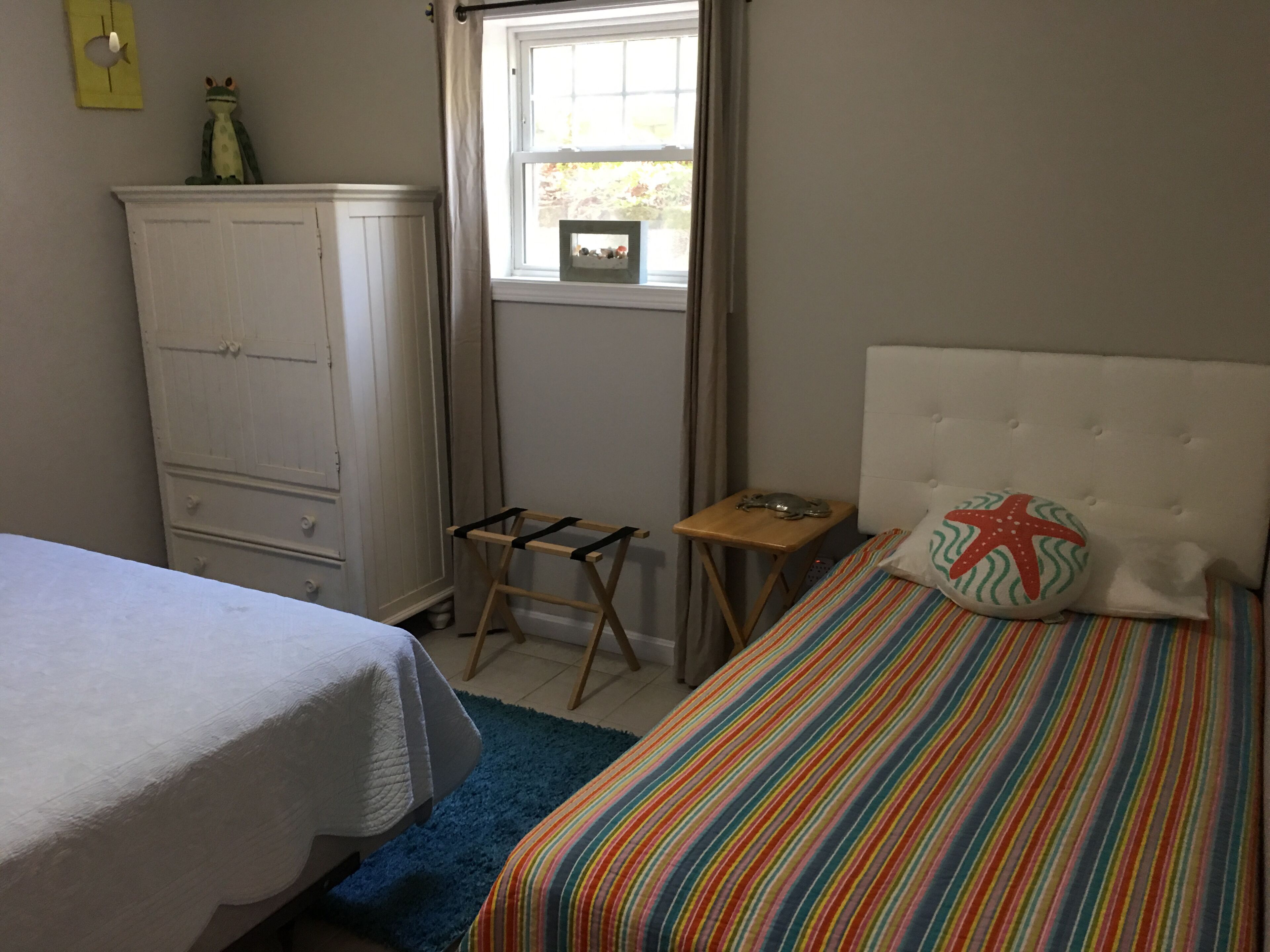 Une chambre à coucher avec un lit, une commode, une fenêtre et une petite table.