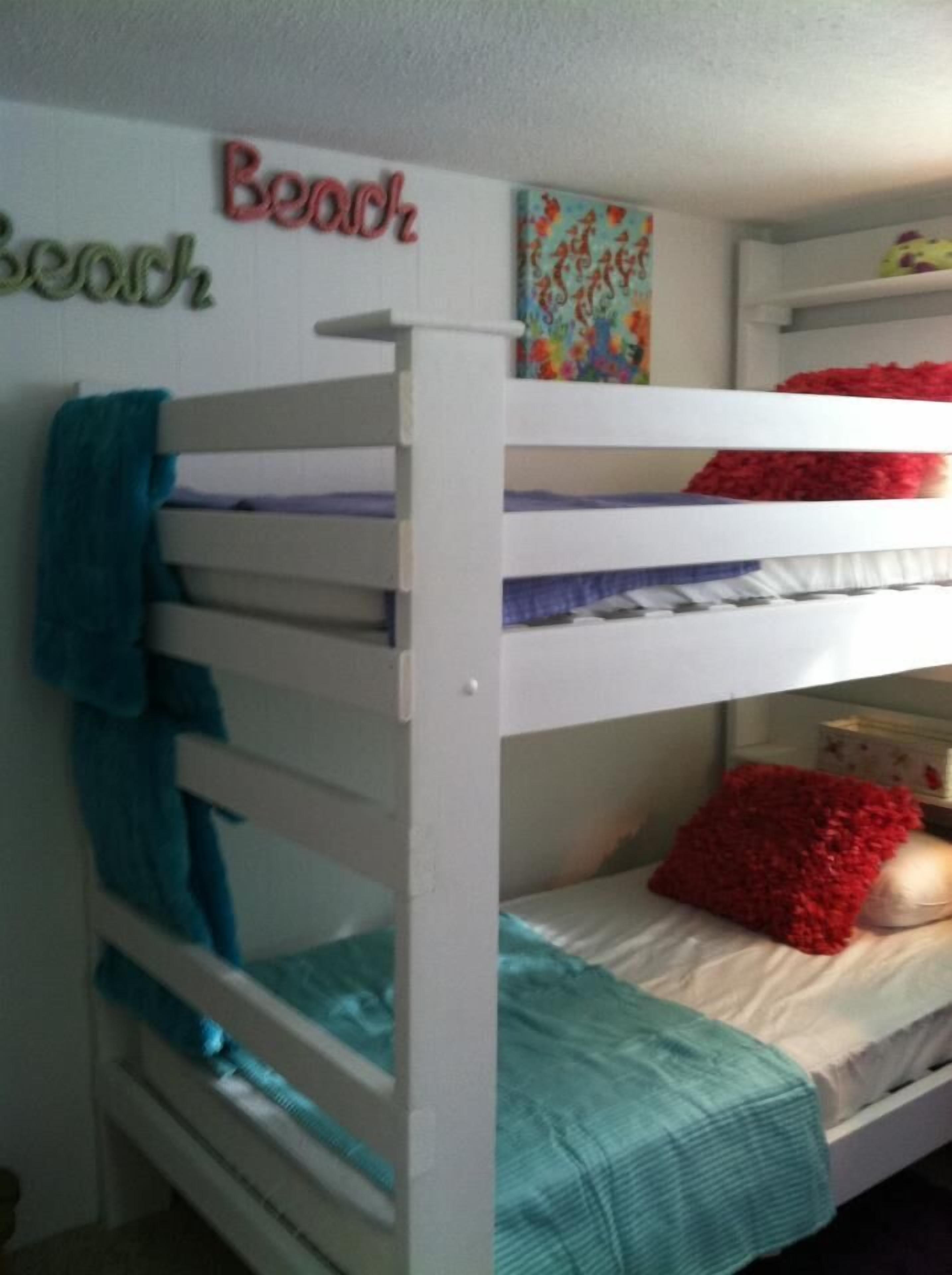 Een stapelbed met een blauwe handdoek op het onderste bed en een rood kussen op het bovenste bed.