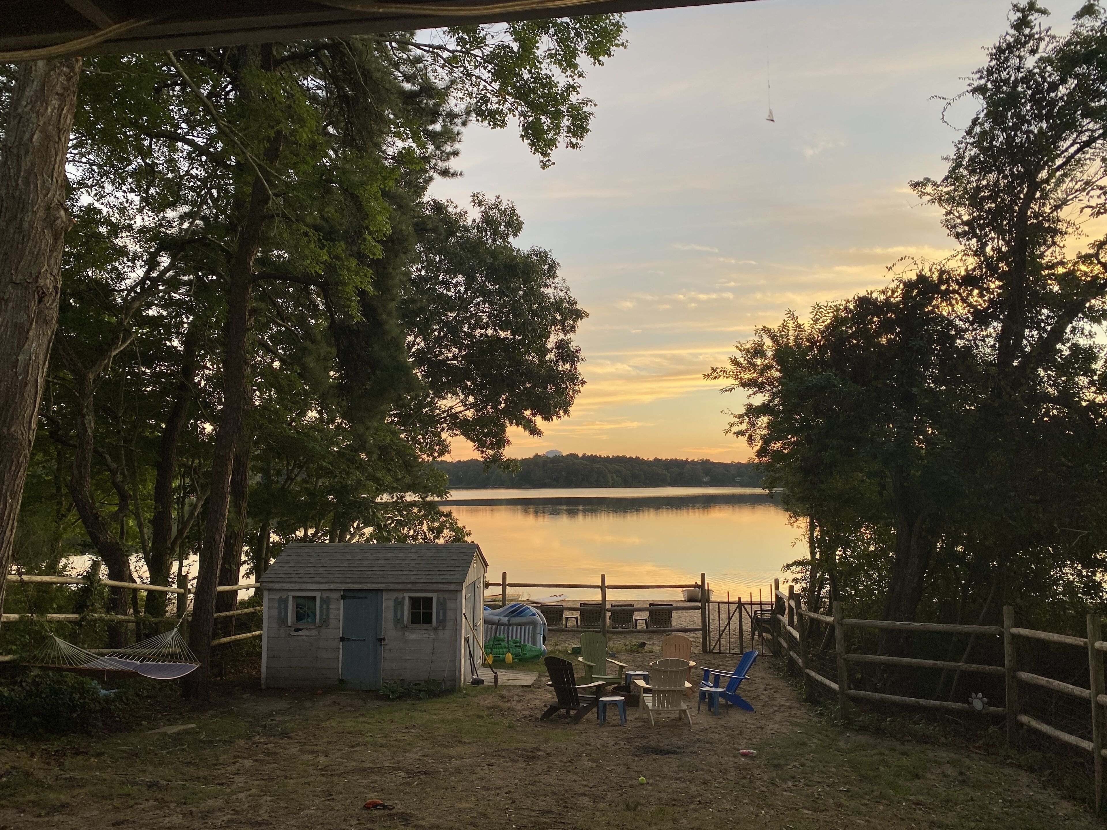 Une propriété au bord du lac, comprenant un petit chalet, un espace de détente extérieur et une clôture en bois.