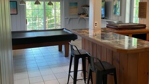 A spacious kitchen with a large island, bar stools, and a view of the outdoors.