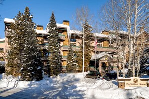 A snow-covered building with multiple balconies and a sign for 'Ptmigan House Condominiums.'