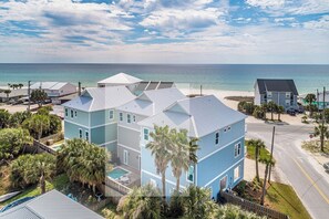 A coastal property with a swimming pool, multiple buildings, and a beach view.