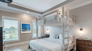 A bedroom with a bunk bed, a dresser, a nightstand, and a painting on the wall.