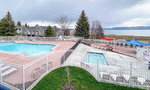 A pool area with a fenced deck, lounge chairs, and a view of a lake and mountains. - Beautiful, Updated Inn Building Condo #204 (Garden City)