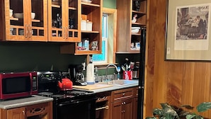 A kitchen with wooden cabinets, a microwave, stove, and a sink.